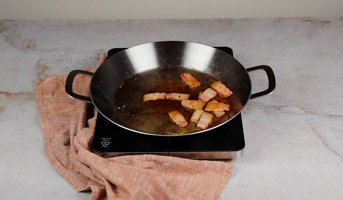 Sofreír la panceta para Arroz al horno en paella