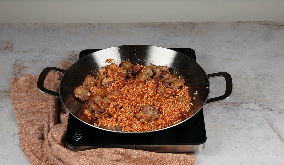 Incorporar arroz y panceta para Arroz al horno en paella 