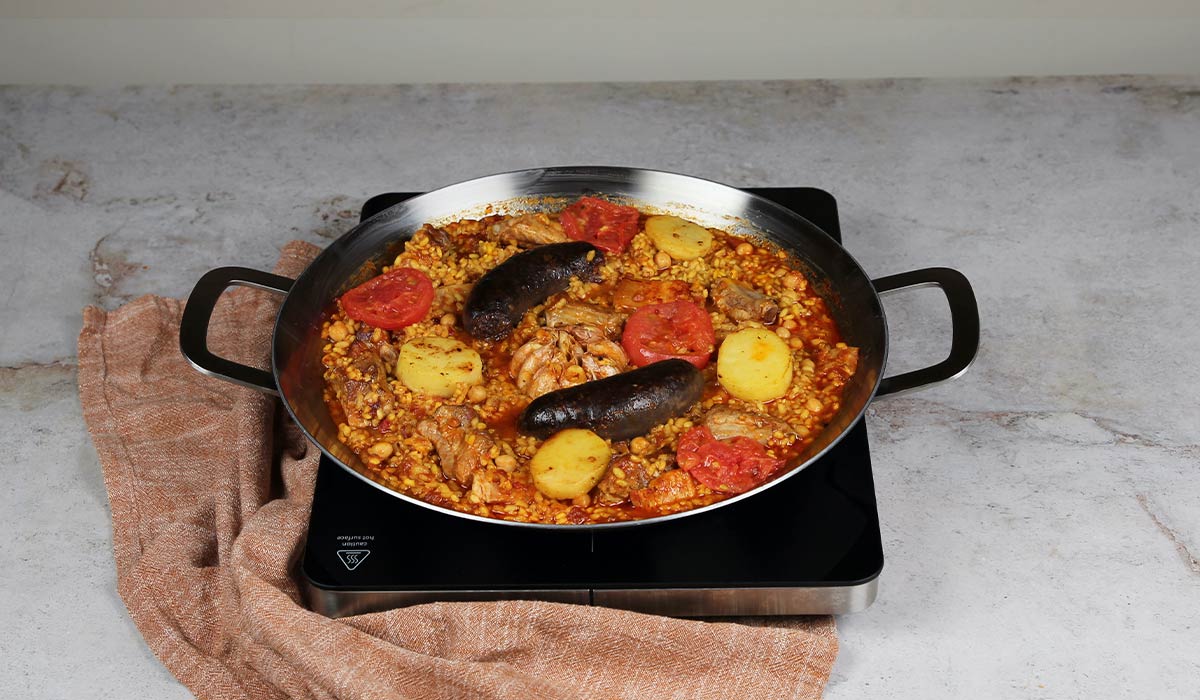 Colocar patatas y tomates en Arroz al horno en paella