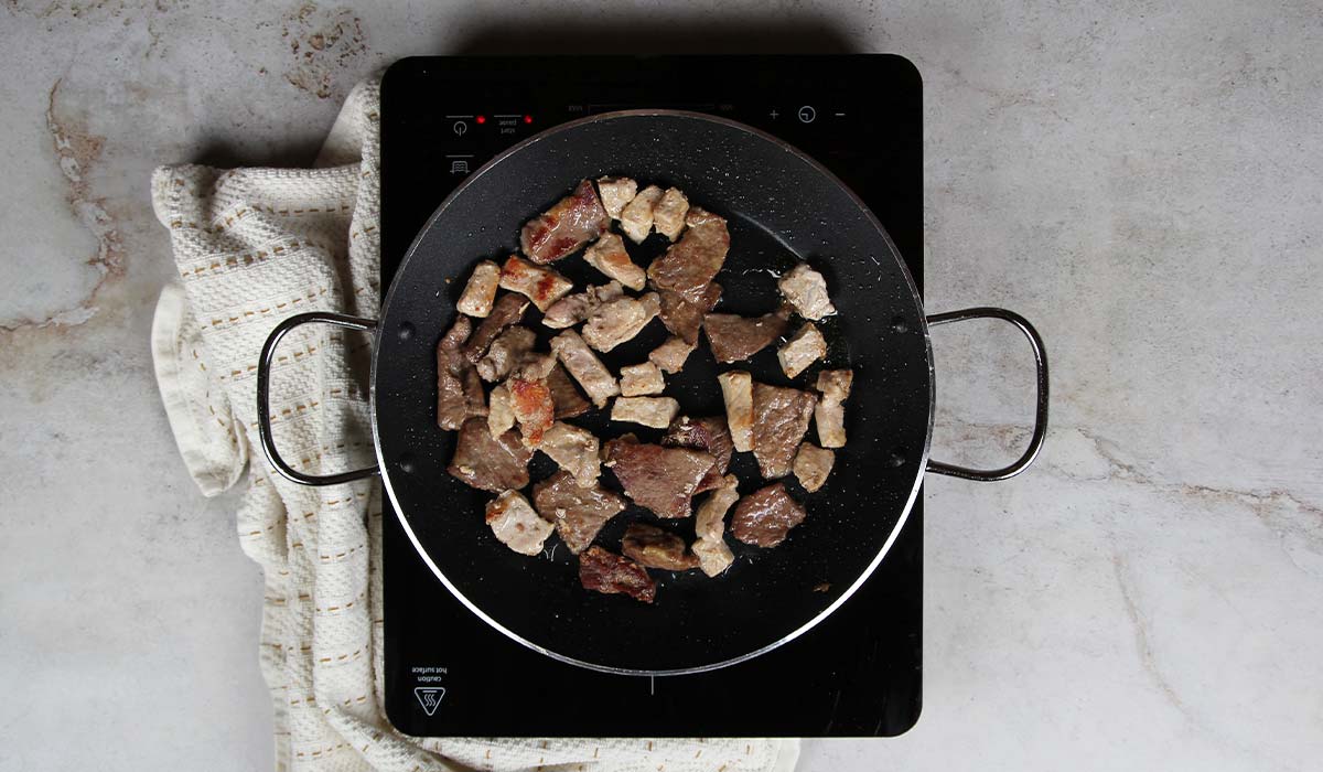 Sofreír carne en Paella de carne de cerdo