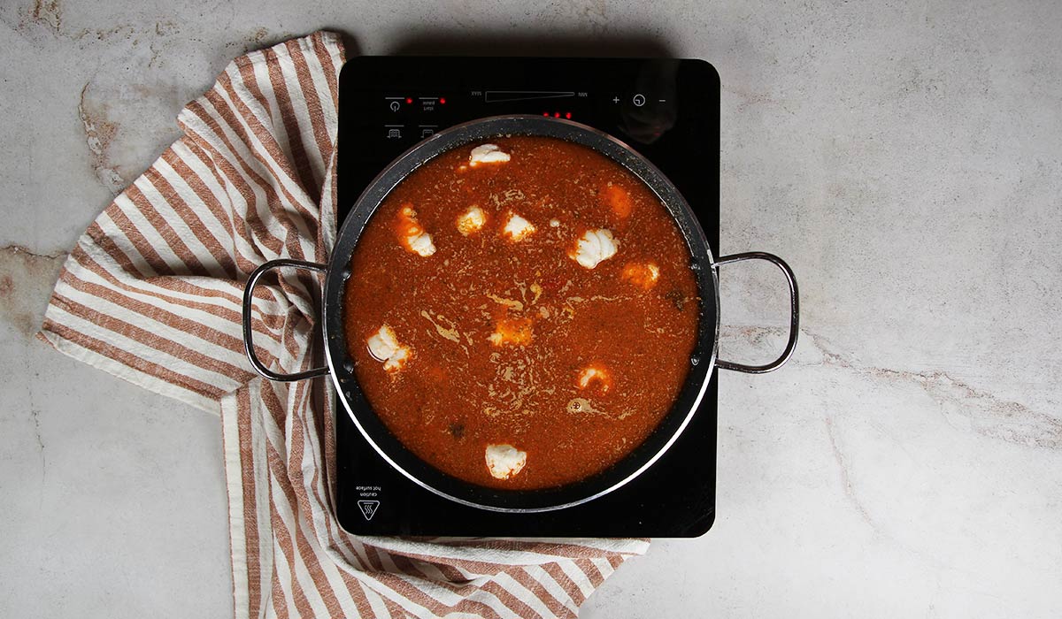 Agregar fideos y caldo a la Fideuá de marisco de la abuela