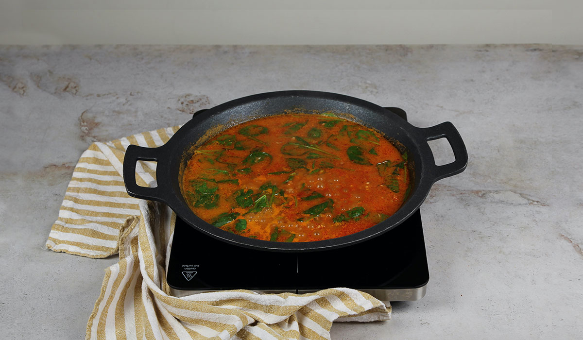 Caldo en paella con boquerones y espinacas