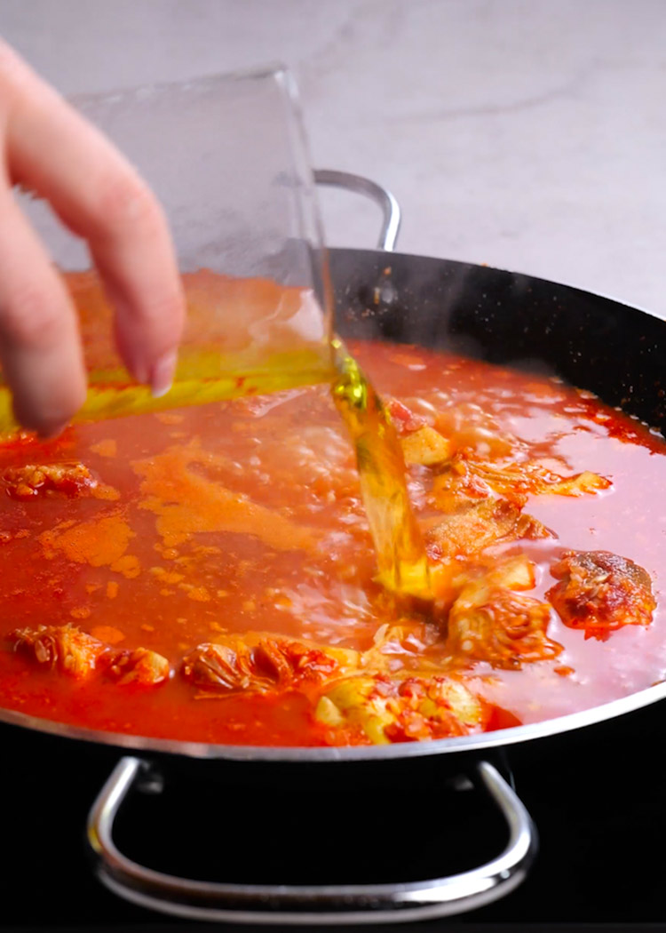 Verter caldo y azafrán en paella de pulpo y alcachofas